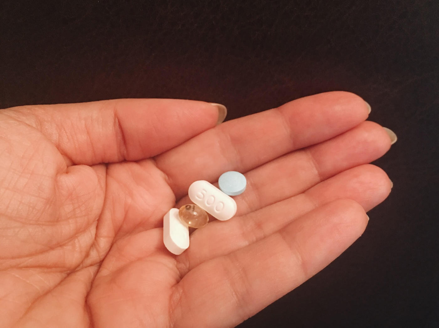 Person holding a few generic brand medications in their hand