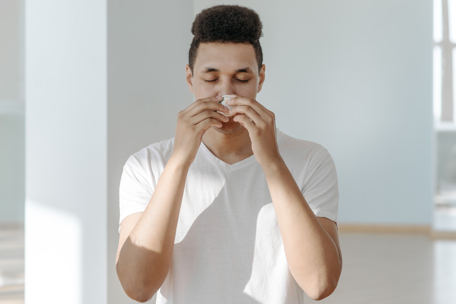 A sick man wiping his nose with a tissue