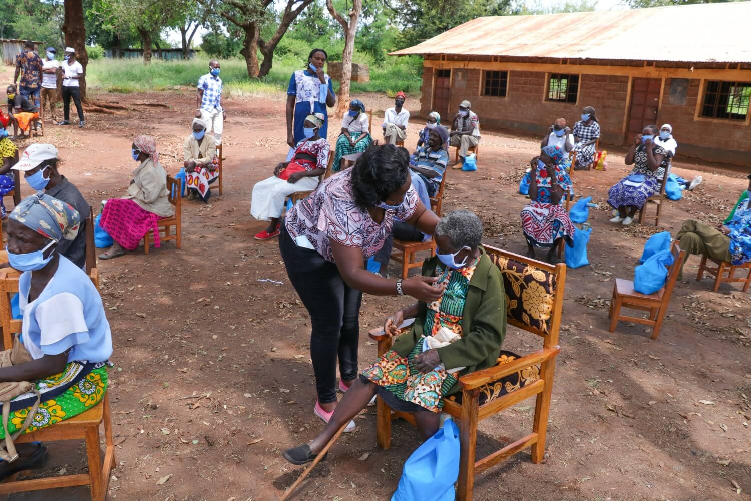 Patients sitting on chairs outside a rural hospital