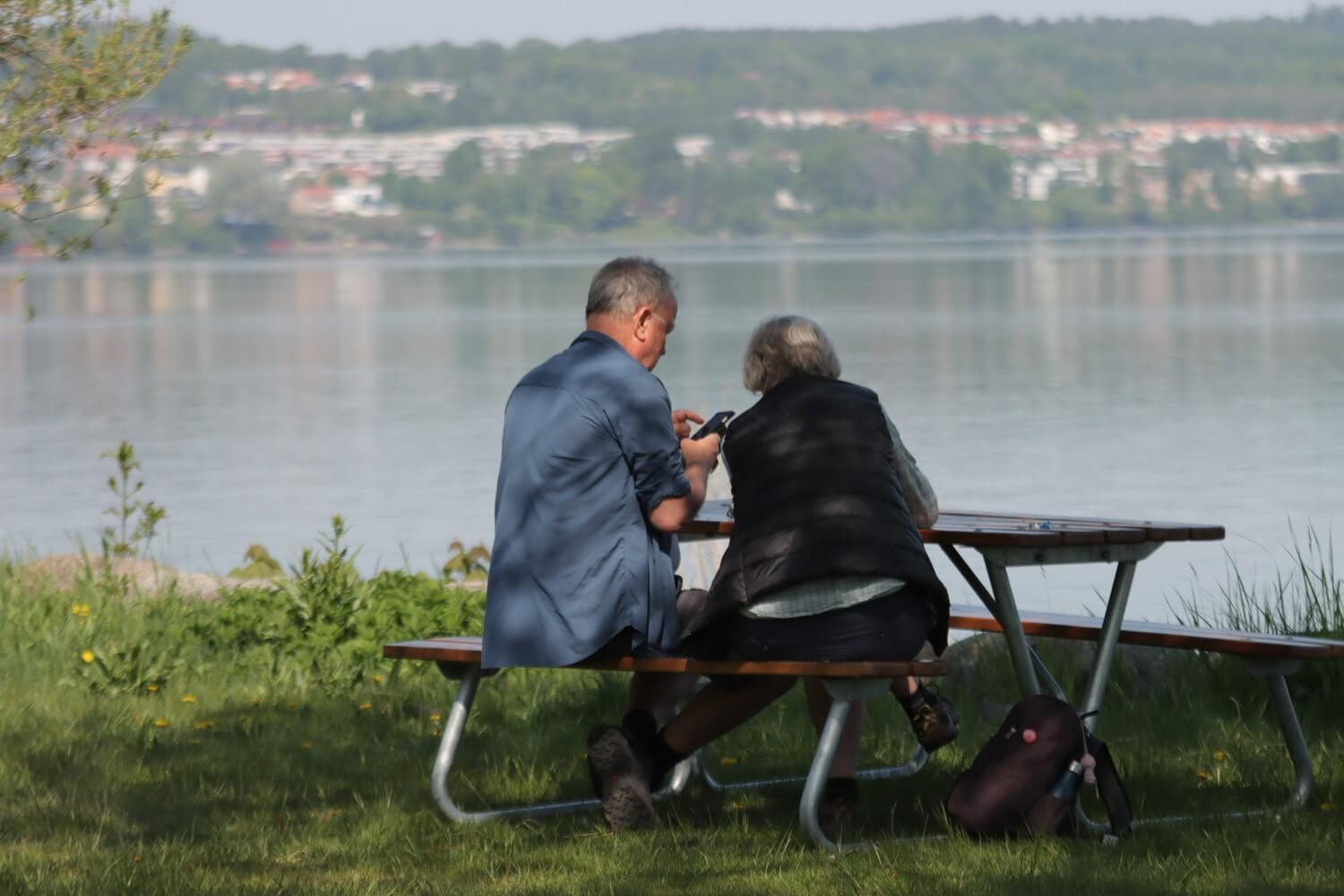 A couple sitting outdoors ordering medications online